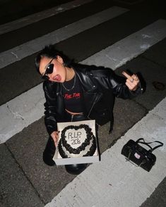 a woman sitting on the ground with a cake in front of her and a camera next to her