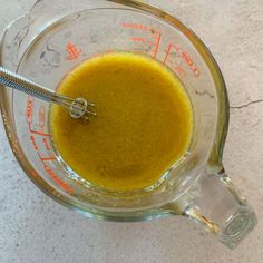 a blender filled with yellow liquid sitting on top of a counter next to a measuring cup