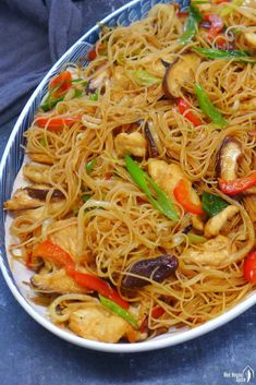 a white plate topped with noodles and veggies on top of a blue table cloth