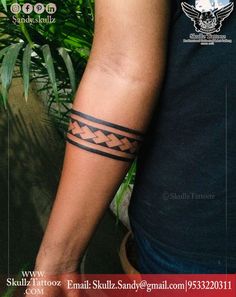 a man with a tattoo on his arm is standing in front of some plants and trees