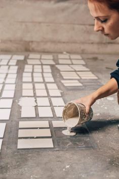 a woman is painting tiles on the ground