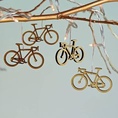 three wooden bicycles hanging from a tree with lights on it's branches in front of a blue sky