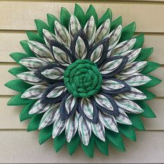 a green and white paper flower hanging on the side of a house's wall