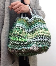 a woman is holding a purse made out of small beads and yarns in her hands