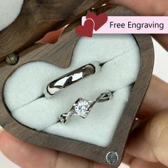 someone is holding a heart shaped box with two engagement rings in it and there are other items inside