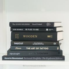 a stack of books sitting on top of a white shelf