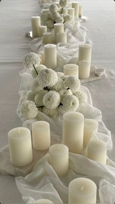 white flowers and candles are lined up on the table