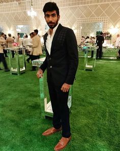 a man in a suit and tie standing on the green carpeted floor at an event