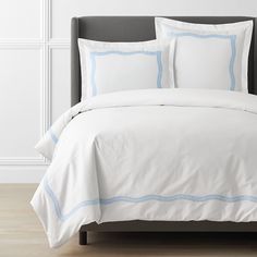 a bed with white sheets and blue trim