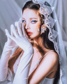 a woman in white gloves and veil posing for a photo with her hands on her face