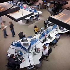 an overhead view of people working at desks with computers and laptops on them