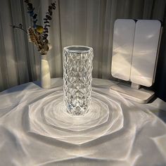 a glass vase sitting on top of a table next to a speaker and other items