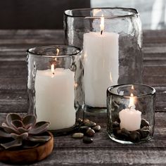 three candles sitting on top of a wooden table next to some rocks and succulents