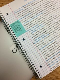 an open notebook with writing on it sitting on top of a wooden table next to a computer mouse