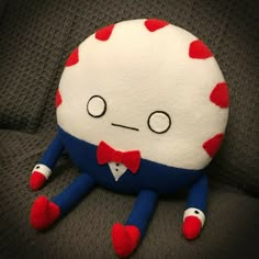 a stuffed animal with red and white hearts on it's face sitting on a couch