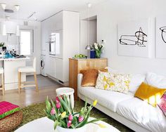 a living room filled with white furniture and flowers in vases on the coffee table