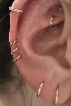 a woman wearing gold ear cuffs and piercings