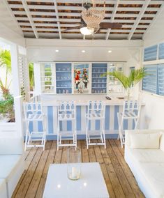 a living room filled with white furniture and a blue bar in the middle of it