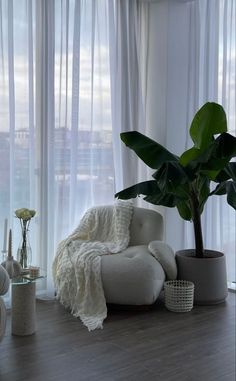 a living room filled with furniture and a large window covered in white sheer curtaines