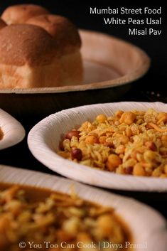 several plates with food on them sitting next to each other in front of bread and rolls