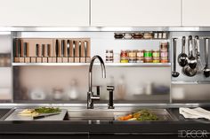 a kitchen with stainless steel cabinets and utensils hanging from the wall above the sink