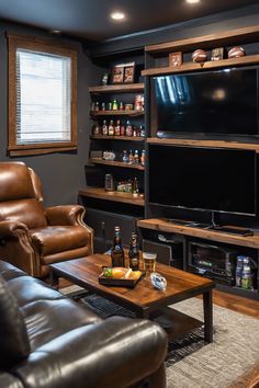 A cozy living room with leather seating, a wooden coffee table holding drinks and snacks, and a large TV with shelves displaying memorabilia and beverages. Farmhouse Man Cave Ideas, Cosy Man Cave, Small Room Man Cave, Small Bar Living Room, Man Cave Ideas Room Small Cheap, Man Cave And Office Combo, Small Basement Man Cave, Small Man Cave Ideas On A Budget, Man Cave Small Room