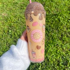 a person holding a cup with an ice cream sundae on it in the grass