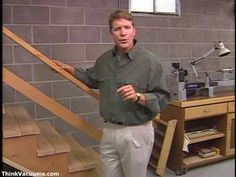 a man standing next to a wooden handrail in front of a brick wall and stairs