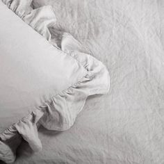 an unmade bed with white linens and pillows on top of it, in black and white