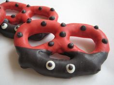 two red and black donuts with googly eyes on white table top next to each other