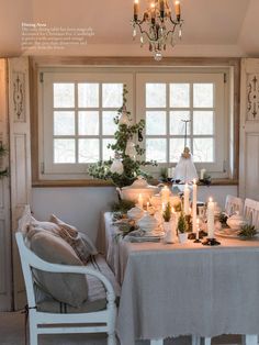 a dining room table with candles on it and christmas decorations in the window sill