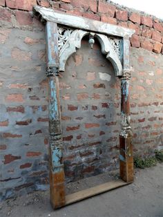 an old wooden arch in front of a brick wall