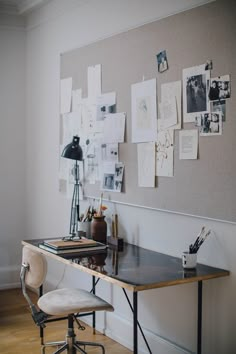 a desk with a chair, lamp and pictures on the wall