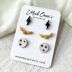 two pairs of earrings with black and white designs on them sitting on top of a sheet