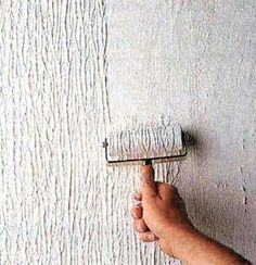 a hand holding a paint roller in front of a white wall