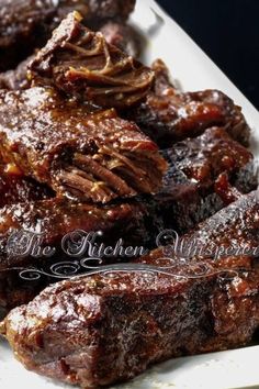 several pieces of meat are on a white platter with black tablecloth and dark background