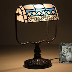 a stained glass lamp sitting on top of a wooden table next to a framed photo