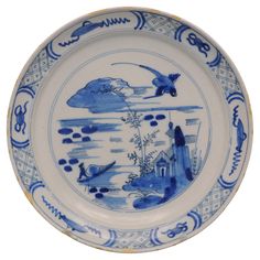 a blue and white plate with an image of birds flying in the sky on it