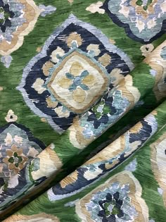 the fabric is green with blue and yellow flowers on it's sides, along with an ornate design