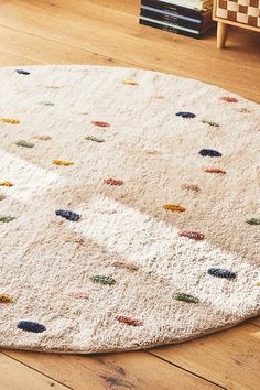 a white rug with multicolored dots on it in a living room area next to a book shelf