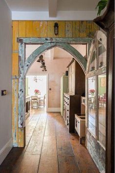 an open door leading to a kitchen with wooden floors and walls, in front of a dining room