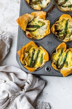 an overhead view of several muffin tins with asparagus and cheese in them