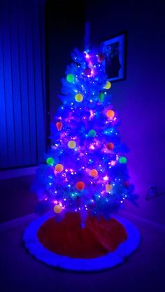 a brightly lit christmas tree in the corner of a room with blue lights on it