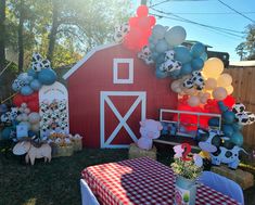 a red barn decorated with balloons and farm animals for a birthday party or baby shower