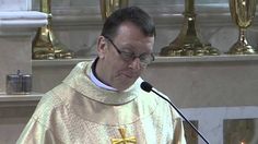 a man standing at a podium in front of a microphone and wearing a priest's outfit