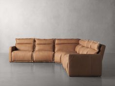 a brown leather couch sitting on top of a gray floor next to a white wall