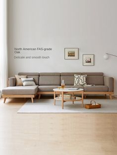 a living room with white walls and wood flooring on the wooden floor is an l - shaped sectional sofa