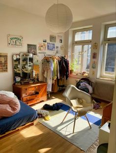 a bedroom with a bed, dresser and hanging clothes on the wall next to a window