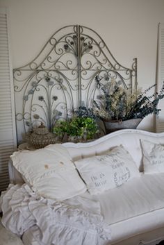 a bed with white sheets and pillows on top of it next to a potted plant