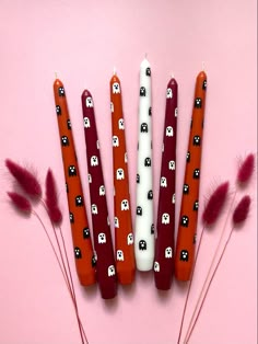 four candles with skulls and bones on them are lined up next to some red feathers